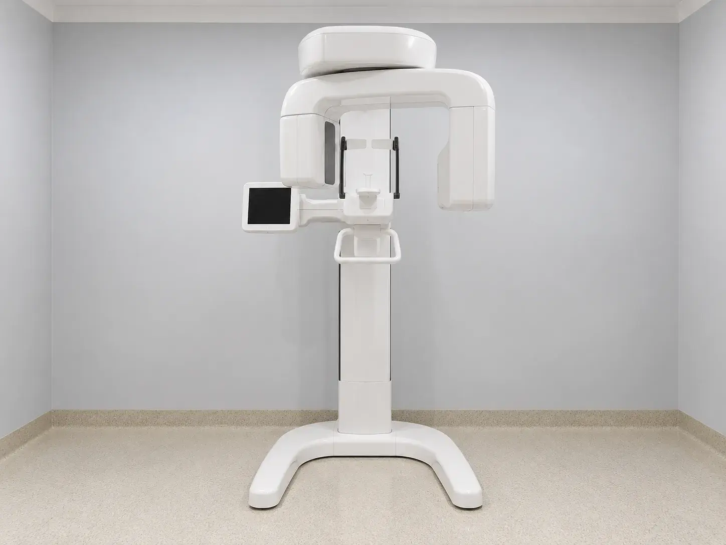 A panoramic dental X-ray machine against a plain wall